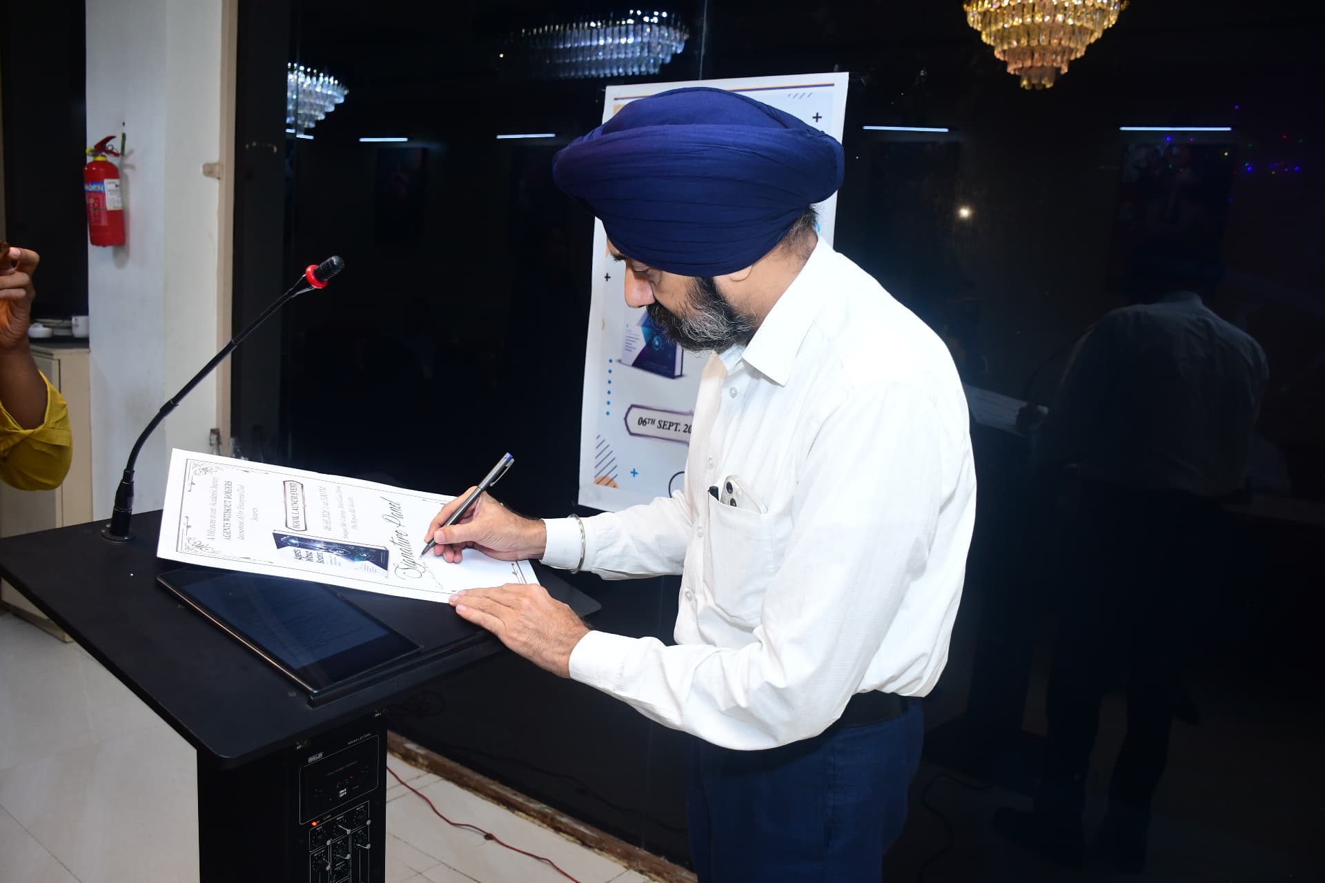 Co-author signing the book publication certificate at the launch event